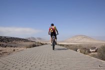 Uomo in mountain bike a cavallo sul marciapiede — Foto stock
