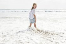 Ragazza in piedi sulla spiaggia — Foto stock
