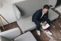 Geschäftsmann mit Notizbuch auf Couch — Stockfoto