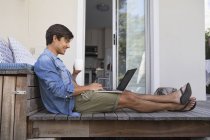 Homme sur la terrasse en utilisant un ordinateur portable — Photo de stock