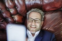 Geschäftsmann liegt auf Ledercouch — Stockfoto