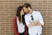 Pareja de pie frente a la pared de ladrillo - foto de stock