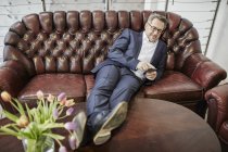 Geschäftsmann auf Couch mit Smartphone — Stockfoto