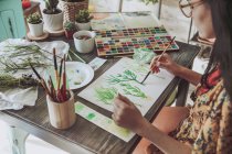 Женщина рисует растения акварелью — стоковое фото