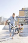 Человек играет с футболом на крыше — стоковое фото