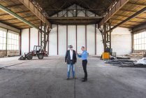 Empresários interagindo no antigo salão industrial — Fotografia de Stock