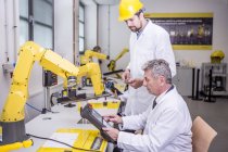 Dos ingenieros en fábrica mirando el dispositivo - foto de stock