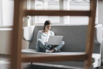 Woman sitting on couch with laptop — Stock Photo