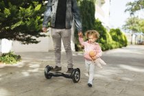 Padre in hoverboard che tiene per mano la figlia — Foto stock