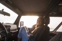Mujer sentada en coche al atardecer - foto de stock