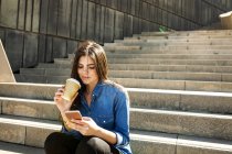 Mulher sentada nas escadas com café para ir — Fotografia de Stock