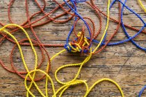 Closeup view of colorful tangled strings on wooden surface — Stock Photo
