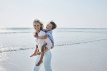 Mother carrying son piggyback — Stock Photo