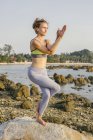 Woman practicing yoga on beach — Stock Photo