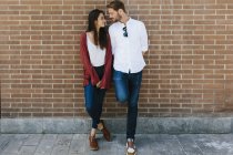 Pareja de pie en la pared de ladrillo - foto de stock