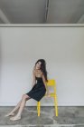 Woman sitting on yellow chair — Stock Photo