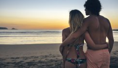 Junges Paar beobachtet Sonnenuntergang am Strand — Stockfoto