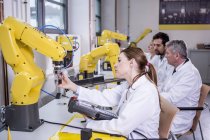 Ingenieros examinando robots industriales - foto de stock