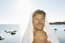 Uomo con asciugamano di fronte al mare — Foto stock