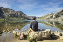 Людина сидить в озерах та — стокове фото