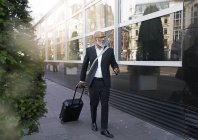 Бізнесмен, що йде вулицею з валізою — стокове фото