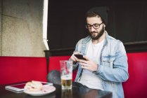 Man text messaging sitting in pub — Stock Photo