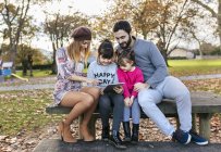 Familie sitzt auf Bank und schaut auf Tablet — Stockfoto