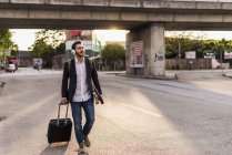 Mann rollt Koffer und Kopfhörer — Stockfoto
