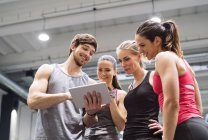 Atletas felices con la tableta en el gimnasio - foto de stock