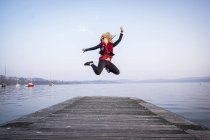 Woman jumping in air on jetty — Stock Photo