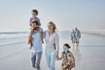 Família estendida passeando na praia — Fotografia de Stock