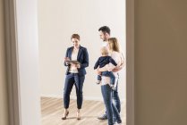 Agente inmobiliario y familia usando tableta en interiores - foto de stock