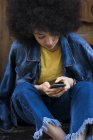 Woman wearing jeans jacket using cell phone — Stock Photo
