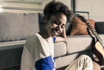 Woman at home next to guitar — Stock Photo