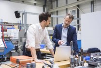 Hombres usando el ordenador portátil en fábrica - foto de stock