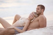 Coppia seduta sulla spiaggia — Foto stock