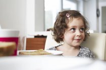Petite fille souriante à table — Photo de stock
