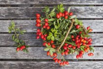 Wickerbasket de rosehips em madeira — Fotografia de Stock