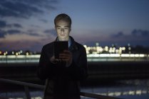 Hombre usando la tableta al aire libre en el crepúsculo - foto de stock