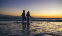 Junges Paar spaziert in der Abenddämmerung im Meer — Stockfoto
