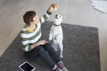 Frau sitzt auf dem Boden und spielt mit Hund — Stockfoto