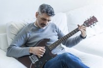 Portrait of mature man playing guitar — Stock Photo