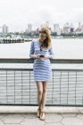 Jovem mulher de pé em Manhattan e usando smartphone — Fotografia de Stock