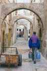 Marrocos, Essaouira, homem local carregando barris no beco na medina — Fotografia de Stock