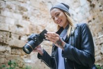 Young woman looking at photos on her camera. — Stock Photo