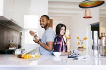 Portrait of young couple standing back to back in kitchen — Stock Photo