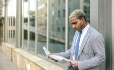 Homme d'affaires appuyé contre le mur et la lecture de journal — Photo de stock