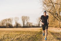 Portrait of young man running in field — Stock Photo