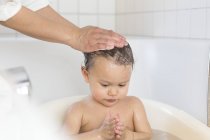Hände der Mutter baden Baby-Mädchen in einer Wanne — Stockfoto