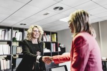 Duas mulheres de negócios apertando as mãos no escritório — Fotografia de Stock